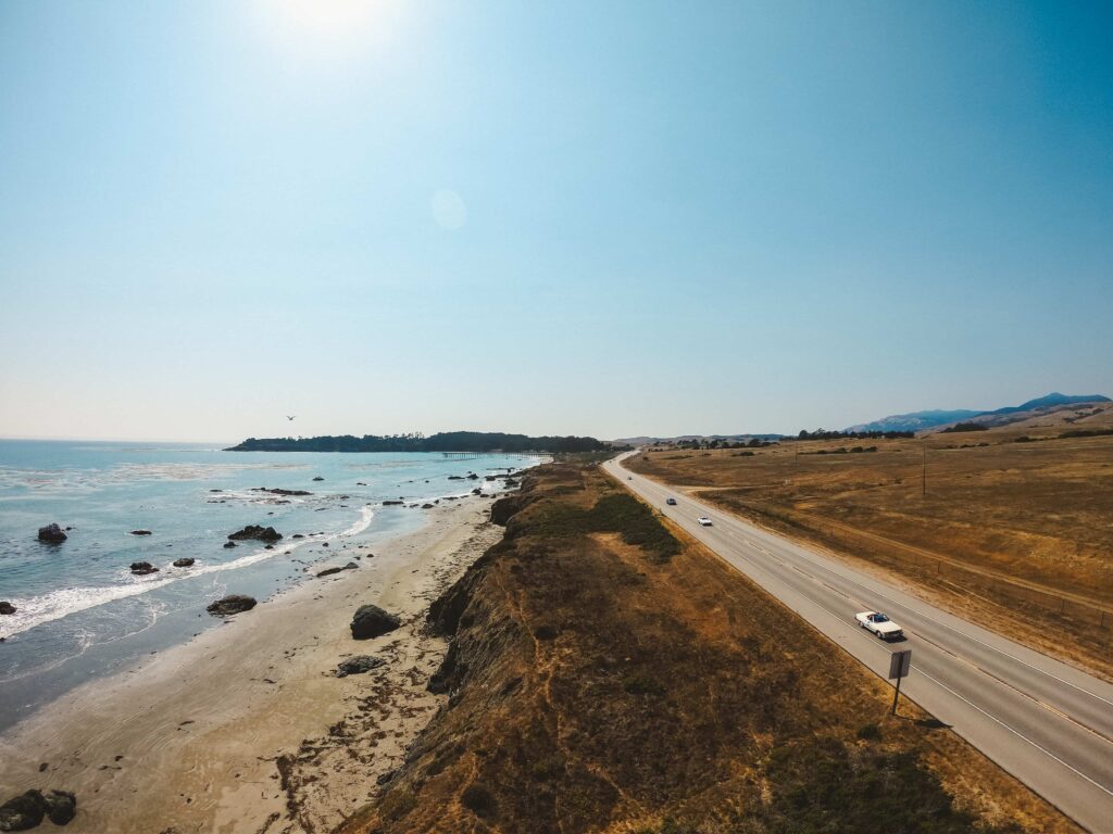 Overhead view of cars driving along a highway next to a beach coast.