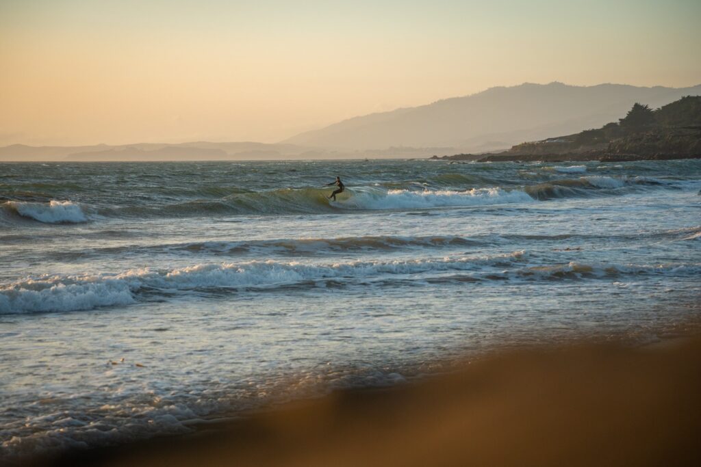 Surfer riding a wave on a beach during a sunset.