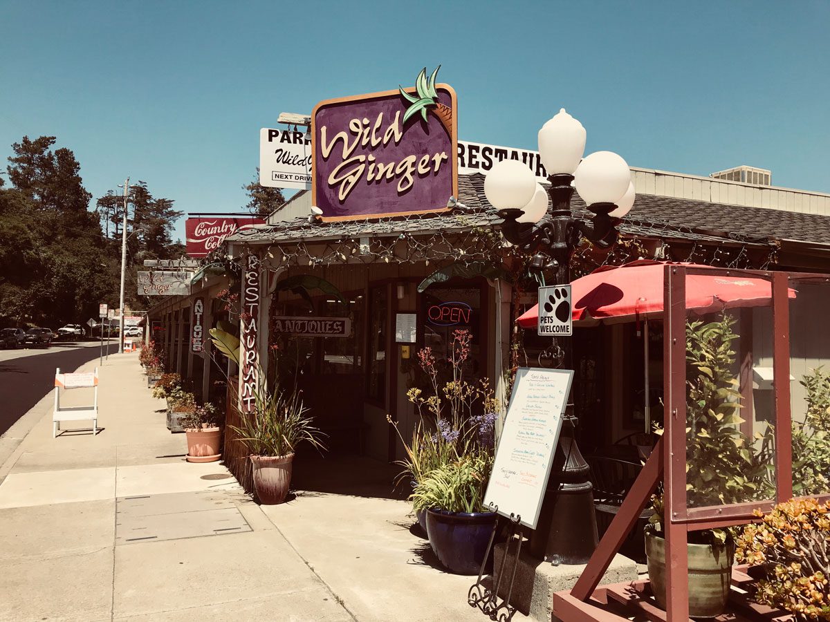 A cozy sidewalk scene featuring a bustling restaurant with outdoor seating and people enjoying their meals.