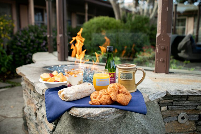 A tray of various breakfast items are laid on a napkin next to a fire pit.